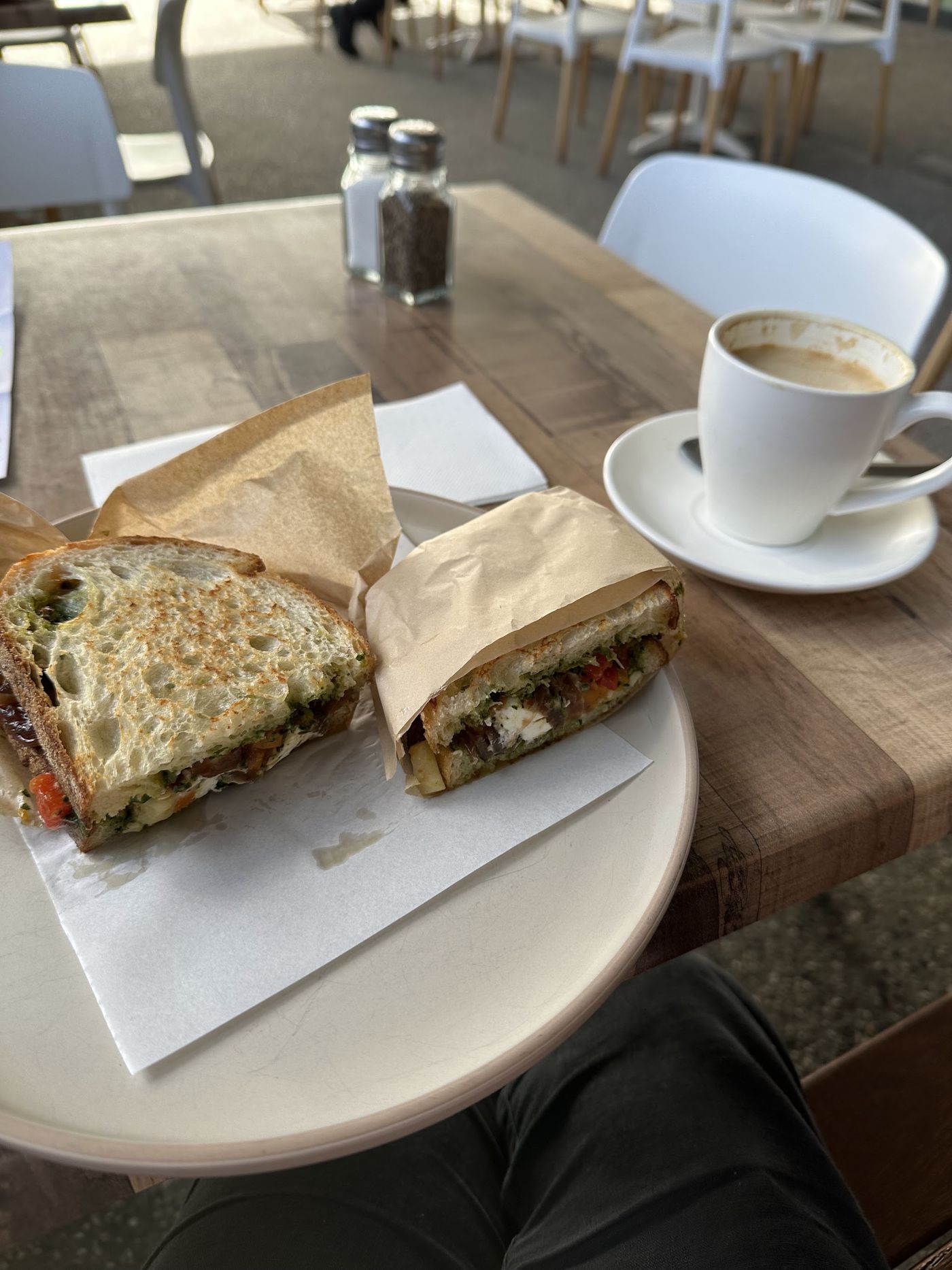 Toasted sandwich and a coffee on an outdoor table at AM Cafe